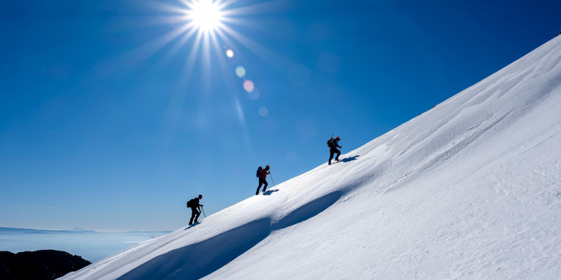 3 people walking up a hill in snow
